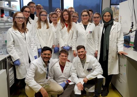 Eine Gruppe von jungen Wissenschaftlern und Wissenschaftlerinnen in Laborkitteln